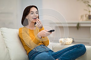 Happy young woman relaxing at home, watching TV