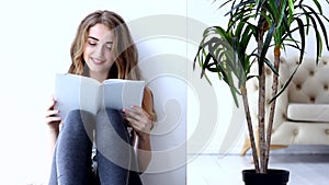 Happy young woman relaxing and reading the book at home