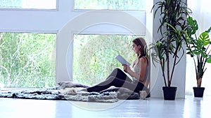 Happy young woman relaxing and reading the book at home