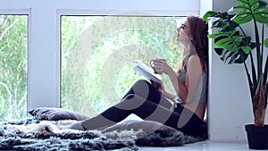 Happy young woman relaxing and reading the book at home