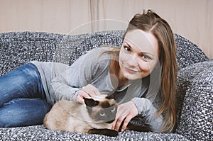 Happy young woman relaxing on sofa with cat