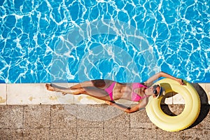 Happy young woman resting near the swimming pool