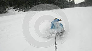 Happy young woman ridet on snowtube behind the ATV Quad bike