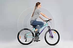 Happy young woman riding bicycle on background