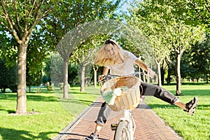 Happy young woman riding bike on road in park, beautiful hipter teenager having fun and laughing