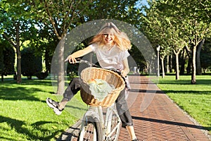Happy young woman riding bike on road in park, beautiful hipter teenager having fun and laughing