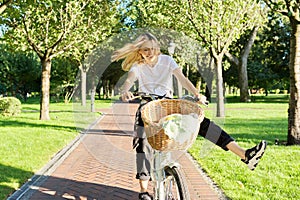 Happy young woman riding bike on road in park, beautiful hipter teenager having fun and laughing