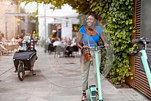 Happy young woman riding an electric scooter in the city