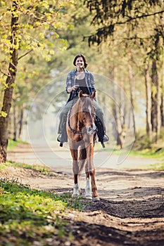 Happy young woman riding horse with cordeo
