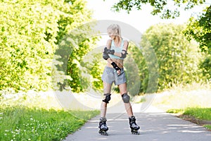 Happy young woman in rollerblades riding outdoors