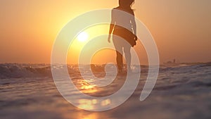 Happy young woman runs and jumps on the sea barefoot to the sun at amazing golden sunset in slow motion. 1920x1080