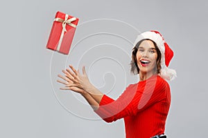 Happy young woman in santa hat catching gift box