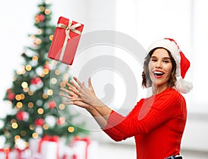 Happy young woman in santa hat catching gift box
