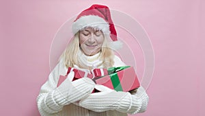 Happy young woman in a Santa hat holding a Christmas present gift box