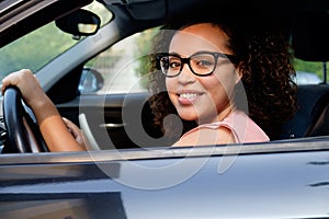 Happy young woman seated in her new car