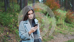 Happy young woman sending sms, texting in the park