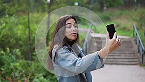 Happy young woman sending sms, texting in the park