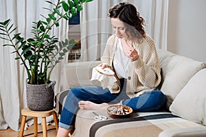 Happy young woman sewing in comforts of her apartment, embroiders a picture