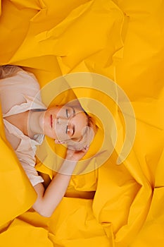 Happy young woman with short hair lying on her back on yellow cramped paper