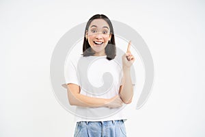 Happy young woman showing advertisement, pointing up, eureka moment, girl has revelation, got an idea, white background