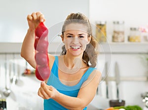 Happy young woman showing bunch of red onions