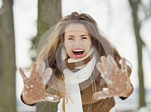 Happy young woman showing hands in snowed gloves