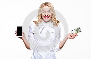 Happy young woman showing mobile phone blank screen and holding a five Euro banknote, smiling with excitement.