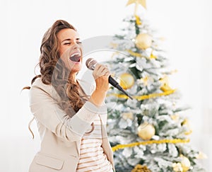 Happy young woman singing near christmas tree