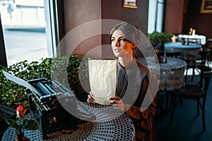 Happy young woman sits by the table in cafe