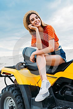 happy young woman sitting on all-terrain vehicle and looking