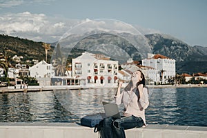 Happy Young woman sitting on Embankment with the laptop. Vacations, freelancer, lifestyle. Successful concept