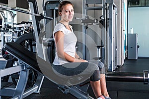 Happy young woman sitting on exercising bench. She`s smiling and looking at camera