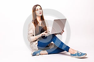 Happy young woman sitting on the floor with crossed legs and using laptop