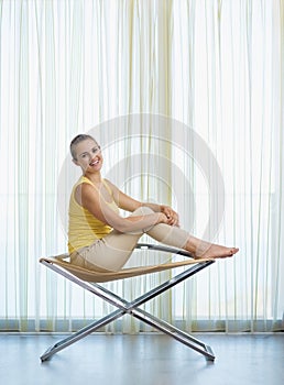Happy young woman sitting on modern chair
