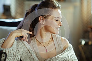 Happy young woman sitting near divan in modern living room