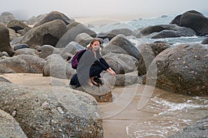 Happy young woman sitting and relaxing on the ocean shore