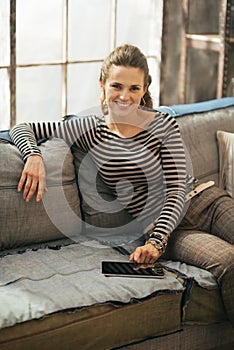 Happy young woman sitting on sofa and using tablet