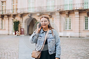 Happy young woman with smartphone calling on city street. Technology, communication and people concept. Positive 30s