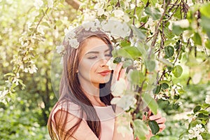 Happy young woman smelling flowers in blossom spring flowers