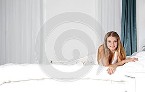 Happy young woman smile while lying on the bed, is