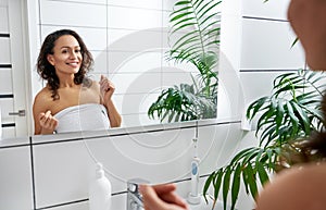 Happy young woman smiling and admiring herself in front of the bathroom mirror