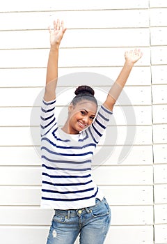 Happy young woman smiling with arms raised