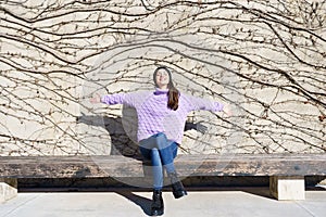 Happy young woman smiling with eyes closed and open arms outdoors.