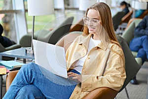 Happy young girl student using laptop computer sitting in university campus.