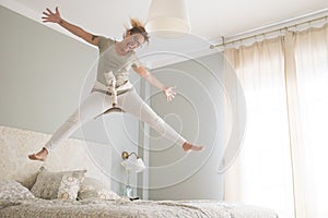 Happy young woman is smiling jumping on bed in the morning wake up - happy female people young adult have fun inthe bedroom with