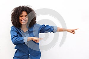 Happy young woman smiling and pointing against white background