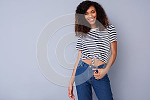 Happy young woman smiling in striped shirt against gray background