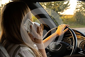 Happy young woman speaking by mobile phone while driving car. Business woman talking phone call in automobile. Unsafely