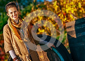 Happy young woman standing near wooden barrel in aut