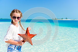 Happy young woman with starfish on white beach in in the nature reserve